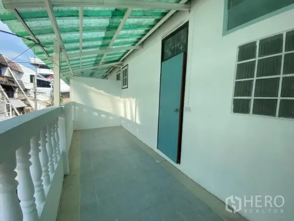 联排别墅 出租在Watthana, Bangkok - 带绿色遮阳棚的长阳台，白色栏杆与侧门。