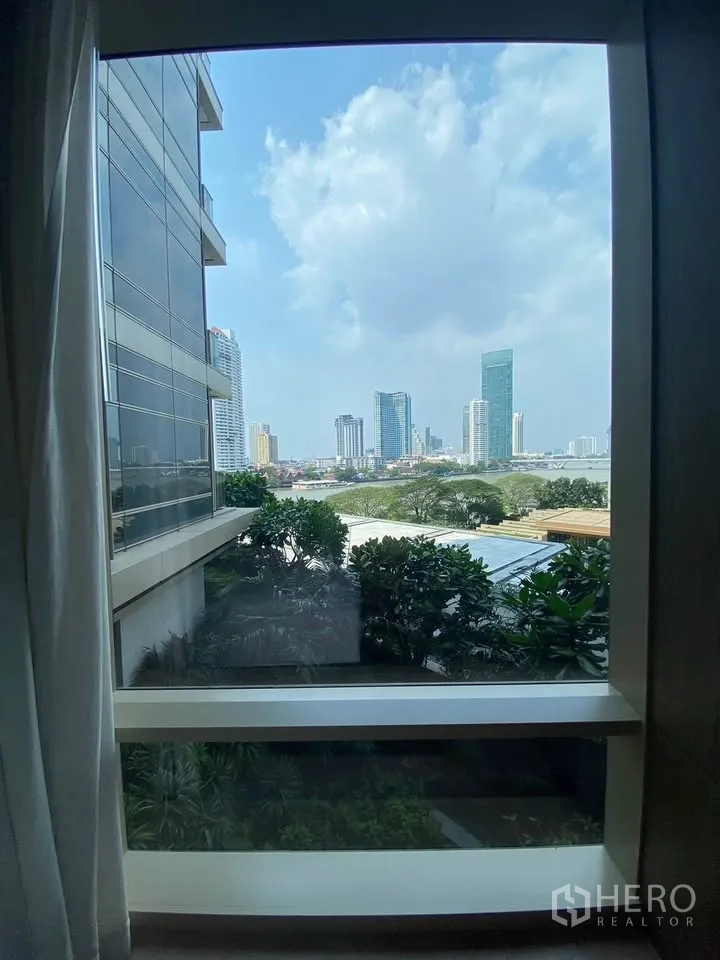 คอนโด for rent in Sathon, Bangkok - วิวสกายไลน์เมืองและแม่น้ำผ่านหน้าต่างบานใหญ่ พร้อมต้นไม้ด้านล่าง.