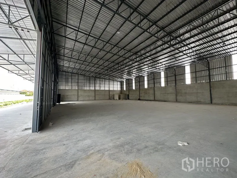 Warehouse for rent in Lam Luk Ka, Pathum Thani - Open-plan storage space featuring tall ceilings, metal framing and side access for loading.