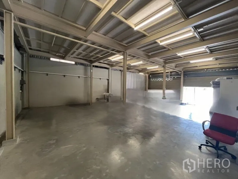 Warehouse for rent in Prawet, Bangkok - Open-plan warehouse interior featuring concrete floor, steel columns and roller doors.