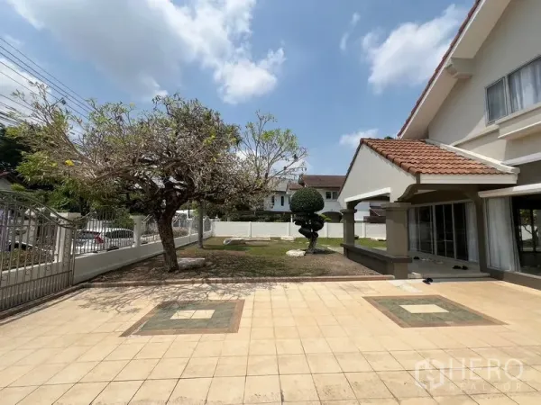 独立式住宅 出售在Mueang Pathum Thani, Pathum Thani - 独立屋前院铺砖庭院，成树与带顶门廊相连。