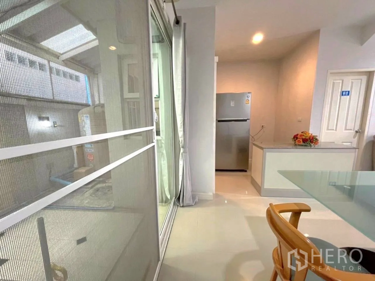 Townhouse for rent in Bang Kho Laem, Bangkok - View toward the kitchen with tall fridge, countertop and sliding glass door.