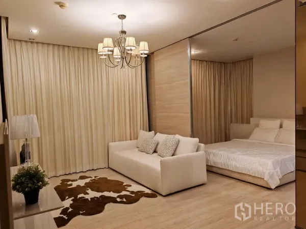 公寓 出租在Watthana, Bangkok - 温馨客厅，沙发与吊灯，卧室设滑动隔断