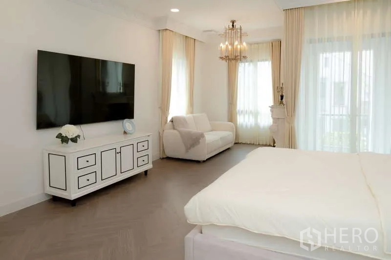 Detached House for rent or sale in Saphan Sung, Bangkok - Master bedroom angle showing wall-mounted TV, sofa seating and full-height curtains.