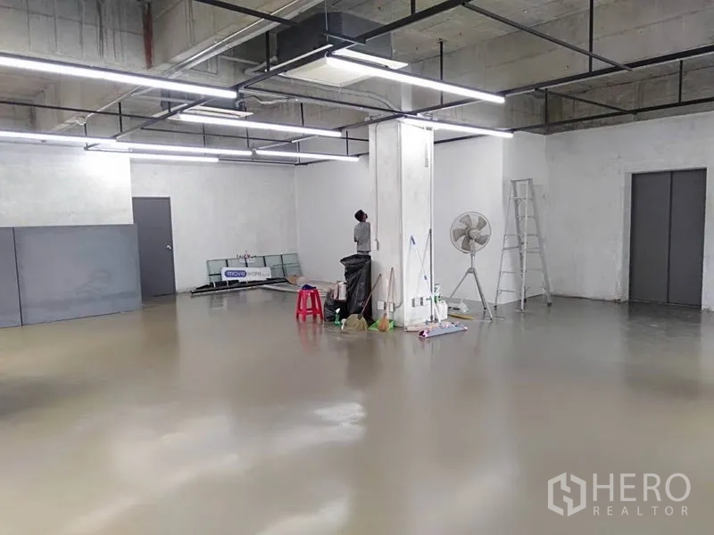 Office Space for rent in Khlong Toei, Bangkok - Spacious industrial-style office area with central column, LED lights, ladder and grey doors under an exposed ceiling