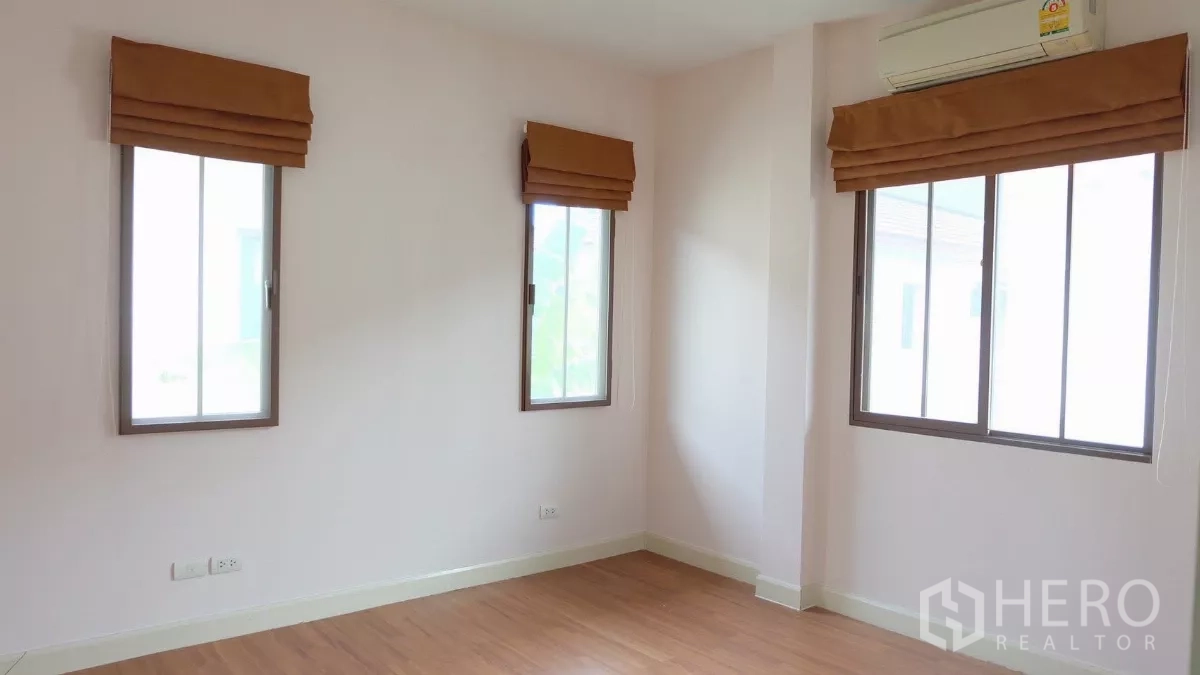Detached House for sale in Bang Phli, Samut Prakan - Corner bedroom with three sliding windows, blinds and wood flooring.