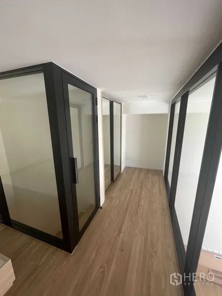 Condominium for rent in Khlong Toei, Bangkok - Glass-partitioned mezzanine corridor with wood floors creating private rooms.