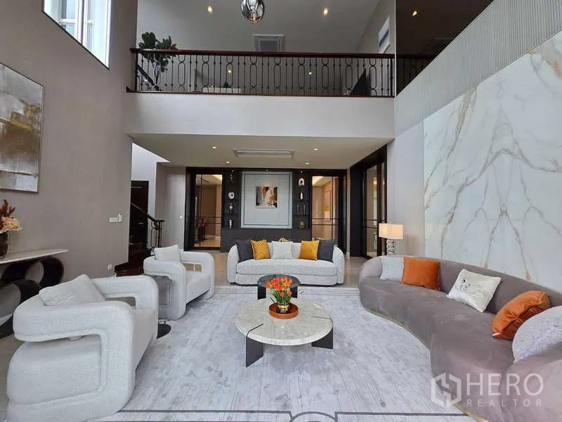 Detached House for rent or sale in Lat Krabang, Bangkok - Double-height living room with gallery balcony and marble feature wall.