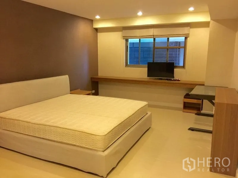 公寓 出租在Watthana, Bangkok - 明亮主卧，配特大床、长条内置书桌、电视与窗户。