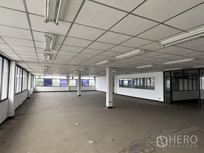 Home Office for rent in Khan Na Yao, Bangkok - Expansive office floor with grid ceiling, fluorescent lights and panoramic windows along two sides.