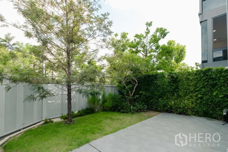 Detached House for rent in Saphan Sung, Bangkok - Landscaped backyard with lawn, mature trees, and tall privacy fence.