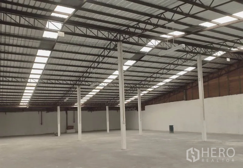 Factory for rent in Bang Pakong, Chachoengsao - Spacious factory interior with steel truss roof, skylight panels, concrete flooring and support columns.