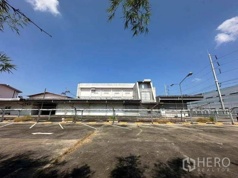 Factory for rent or sale in Thanyaburi, Pathum Thani - Rear view of the factory showing fenced loading docks and marked parking bays.