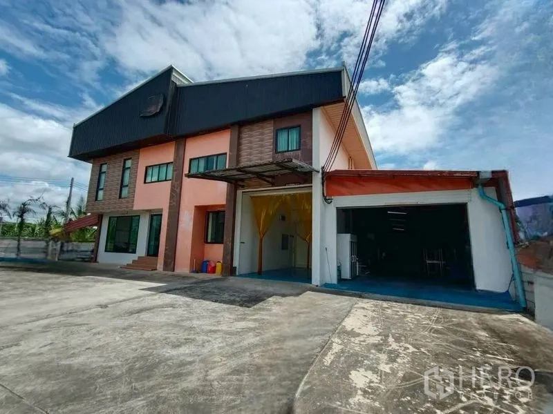 โรงงาน for rent or sale in Krathum Baen, Samut Sakhon - ภายนอกอาคารโรงงานสองชั้นพร้อมลานคอนกรีตกว้างและทางเข้าขนถ่ายสินค้า
