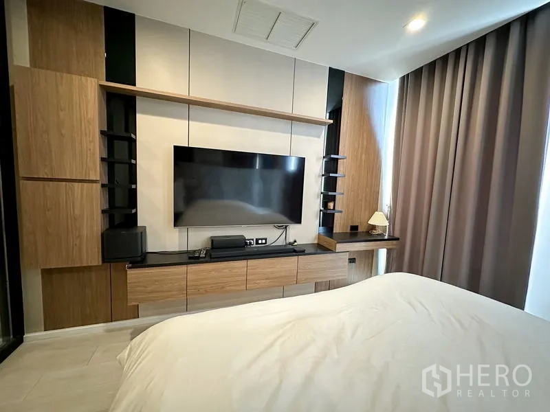 公寓 出租在Pathum Wan, Bangkok - 卧室电视墙，内置收纳与落地窗帘。