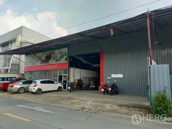 คลังสินค้า ให้เช่าในBang Kapi, Bangkok - ด้านหน้าโกดังติดถนน ผนังเมทัลชีท ประตูม้วนสูง มีชายคาลานขนถ่ายและที่จอดรถ.