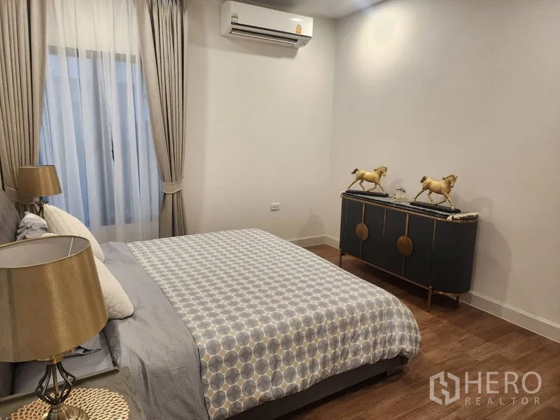 独立式住宅 出租或出售 - 卧室一角，床与金色装饰斗柜，灯光柔和