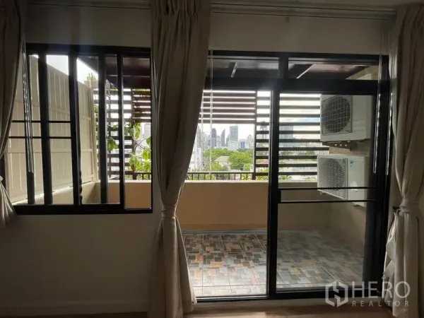 Condominium for rent in Watthana, Bangkok - Covered balcony with sliding glass doors, city view and outdoor AC units.