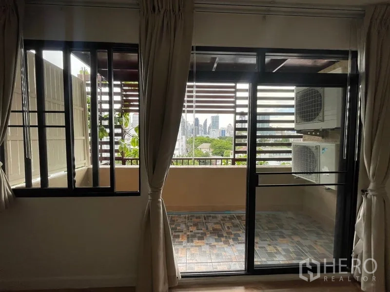 Condominium for rent in Watthana, Bangkok - Covered balcony with sliding glass doors, city view and outdoor AC units.
