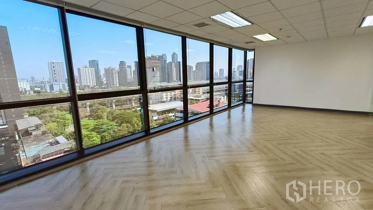 Office Space for rent in Ratchathewi, Bangkok - Corner office with floor-to-ceiling windows, herringbone floors and Bangkok skyline view over greenery.