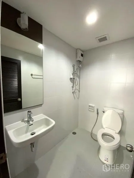 公寓 出租在Watthana, Bangkok - 现代卫浴，白色瓷砖，淋浴配热水器、坐便与台盆镜柜。