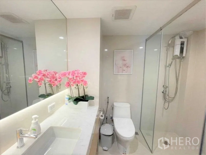 公寓 出售在Bang Rak, Bangkok - 现代浴室，长台盆、超大镜面、坐便与玻璃淋浴间。