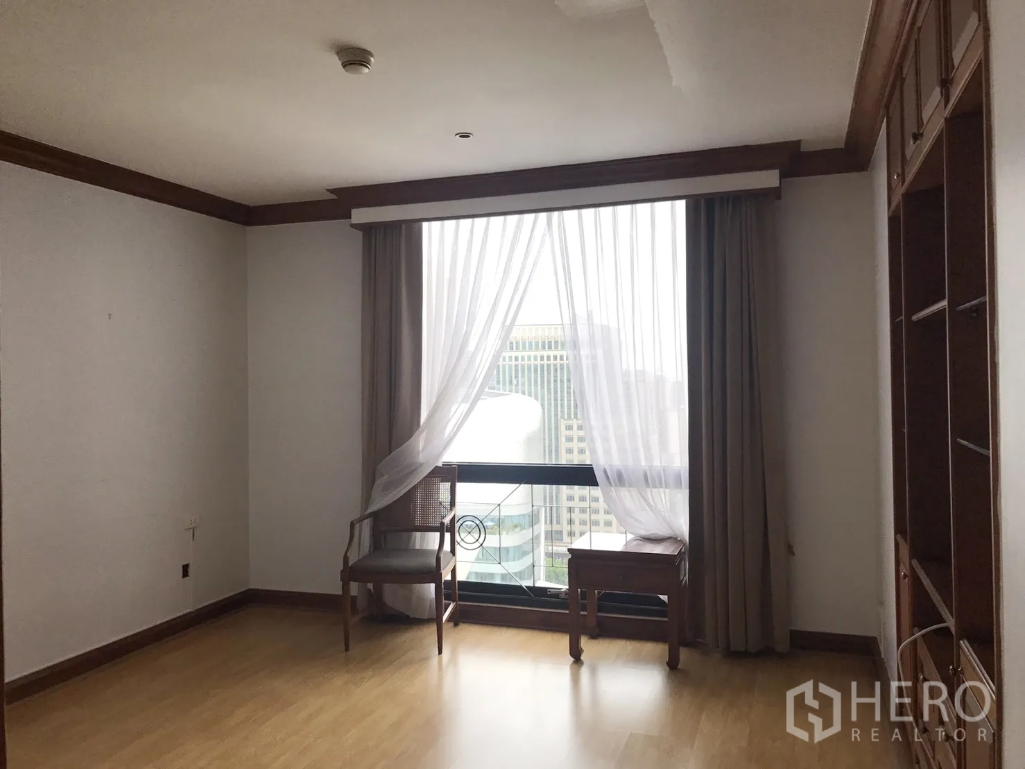 Condominium for rent in Pathum Wan, Bangkok - Corner room with floor-to-ceiling window, sheer curtains, and city skyline view.