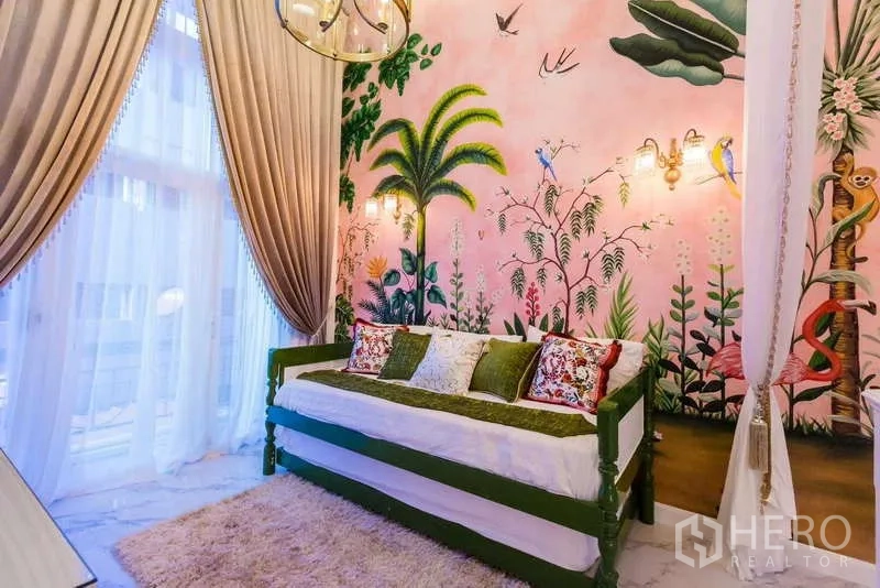 Townhouse for rent in Lat Phrao, Bangkok - Cozy bedroom with tropical mural on pink wall, daybed and floor-to-ceiling curtains.