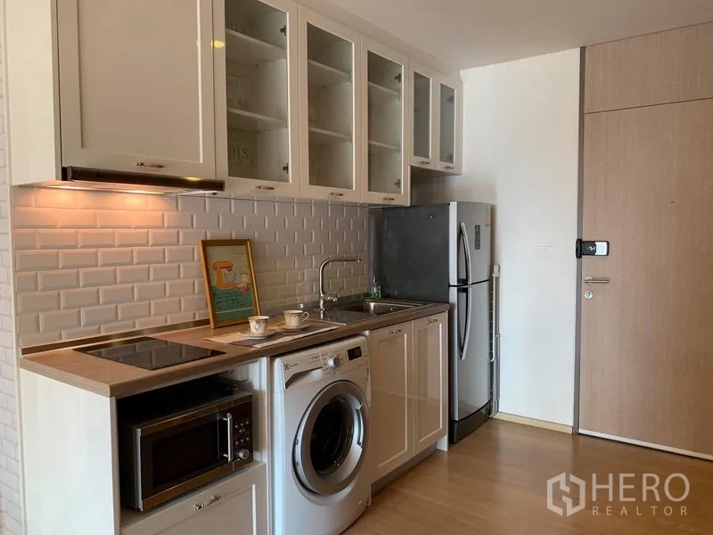 Condominium for rent in Phaya Thai, Bangkok - Compact kitchen with electric hob, sink, microwave, fridge and a front-loading washing machine.