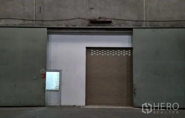Warehouse for rent in Yan Nawa, Bangkok - Industrial entrance with a large sliding door, central roller shutter and a side access door.