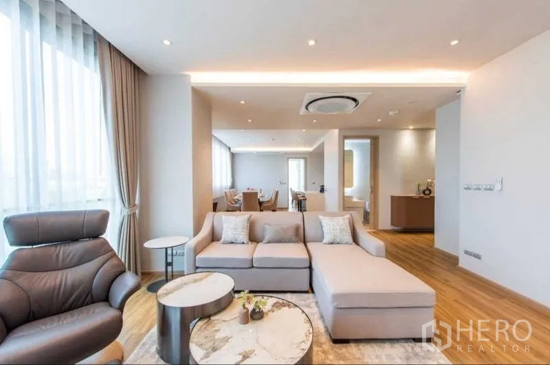 公寓 出租在Bang Na, Bangkok - 现代开放式客厅，L 型沙发、落地窗与木地板，位于邦纳区公寓。