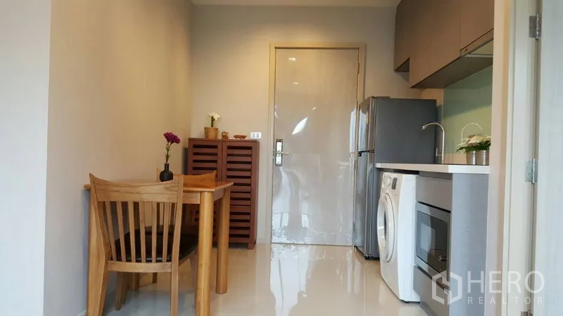 Condominium for rent in Khlong Toei, Bangkok - Dining nook for two next to a modern kitchenette and full-size refrigerator.