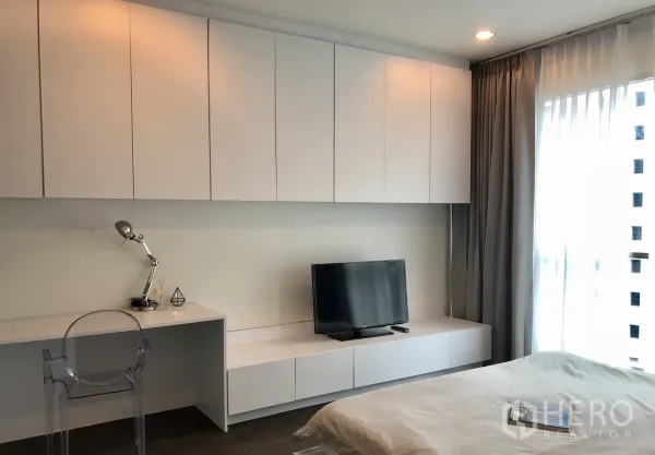 Condominium for rent in Pathum Wan, Bangkok - Bright bedroom with built-in cabinets, work desk, TV console and sheer curtains.