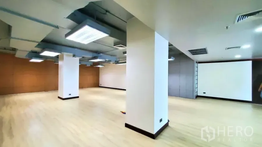 Office Space for rent in Khlong Toei, Bangkok - Spacious open-plan office with light wood floors, white columns, exposed ceiling ducts and LED lighting.