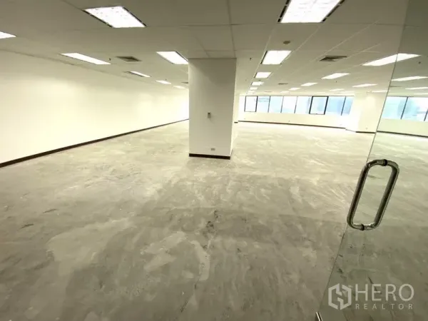 Office Space for rent - Open-plan 145 sqm office with glass entry, white walls, drop ceiling lights and large windows.