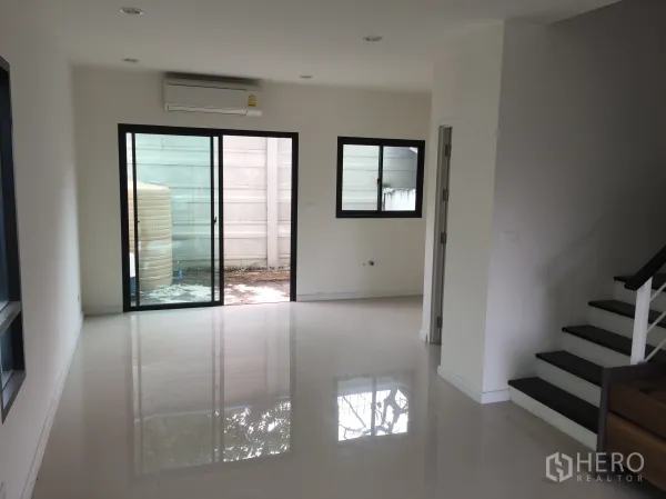 Townhouse for rent in Bang Kapi, Bangkok - Bright ground-floor living area with glossy tile flooring, sliding glass door and window.