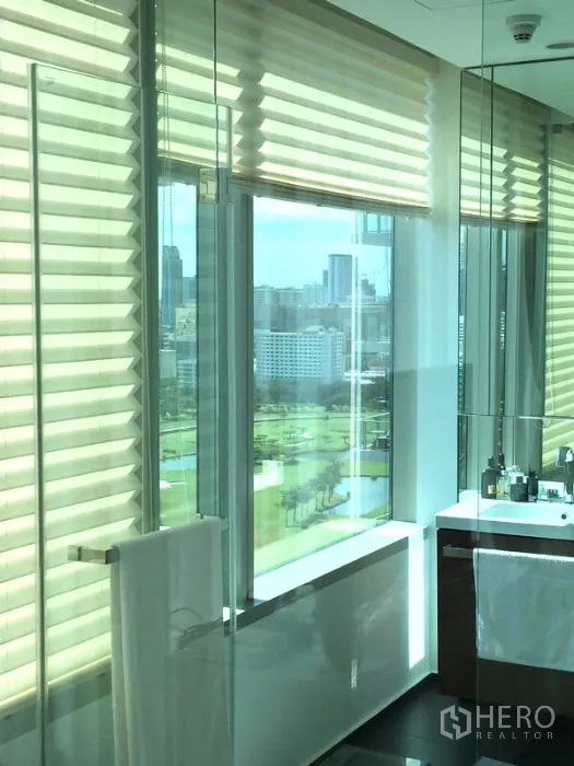 Condominium for rent or sale in Pathum Wan, Bangkok - Bathroom with large mirrors and windows offering city views and blinds