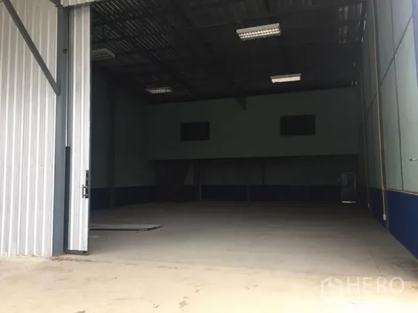 货栈 出租在Lat Krabang, Bangkok - 仓库宽阔入口，金属门半开，前方有装卸空间