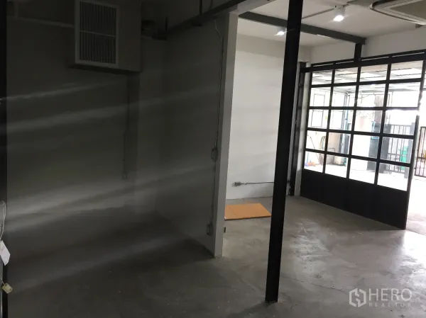 Detached House for rent in Din Daeng, Bangkok - Open-plan ground floor with polished concrete, black-framed glass doors and ceiling lights.