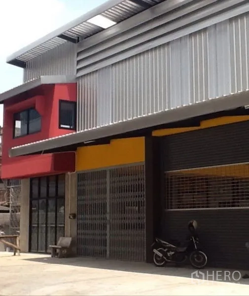 Warehouse for rent in Bang Kapi, Bangkok - Street-facing warehouse facade with bold red and yellow accents and a metal roof.