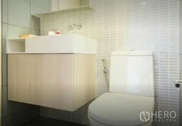 Condominium for rent in Phaya Thai, Bangkok - Bright bathroom with floating vanity, white toilet and light gray tiled walls in the condo.