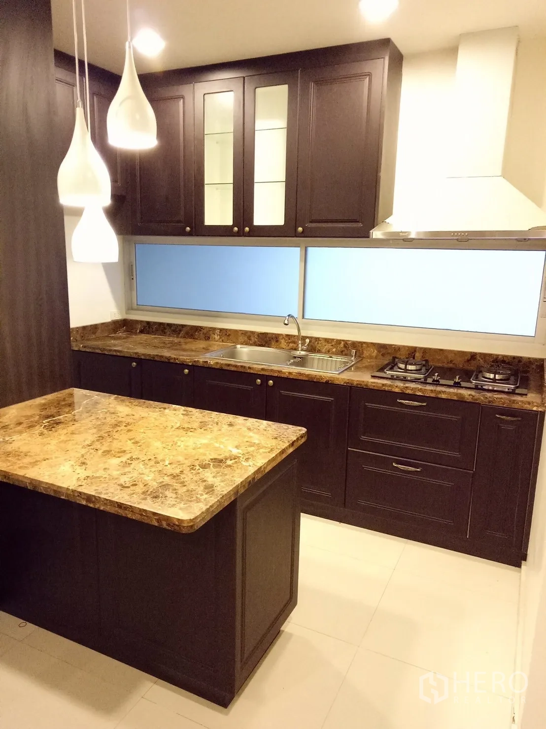 Townhouse for rent in Suan Luang, Bangkok - Modern kitchen with marble island, gas hob, range hood and dark wood cabinetry