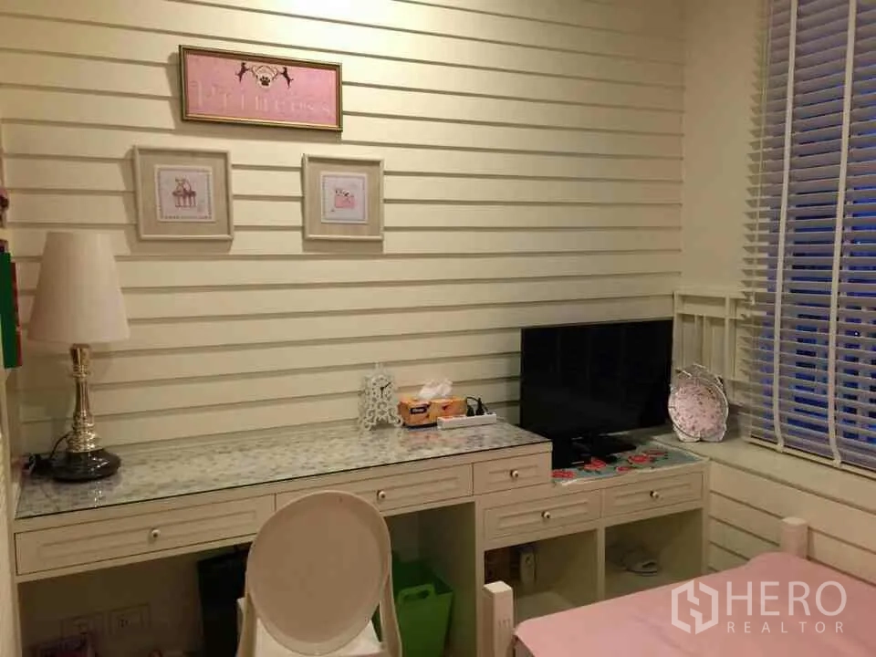 Condominium for rent or sale in Watthana, Bangkok - Cozy secondary bedroom with a long built-in study desk, TV and window blinds.