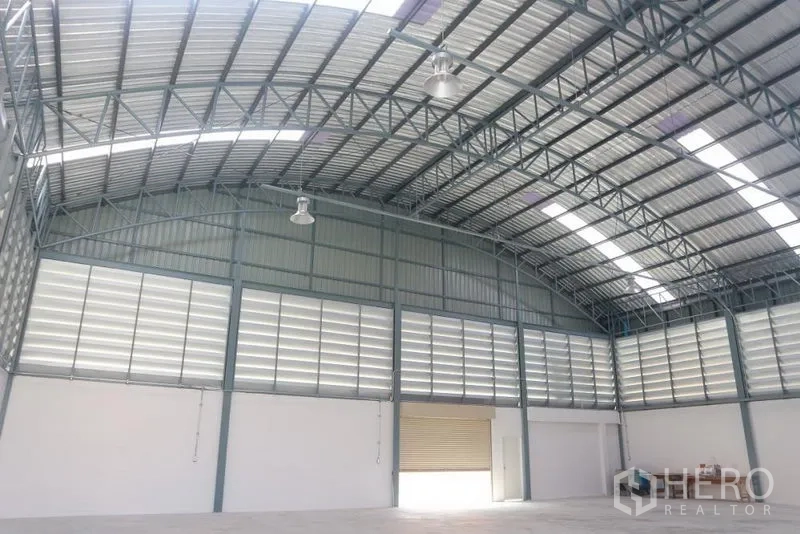 Factory for sale in Bang Pakong, Chachoengsao - Wide clear-span warehouse with roller shutter door and ventilated side walls.