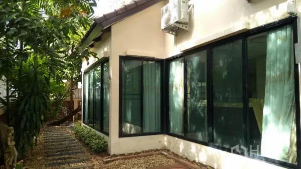 Detached House for rent - Side garden path with stepping stones beside large black-framed windows and an outdoor AC unit.