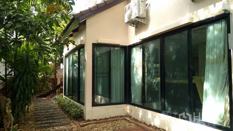 Detached House for rent - Side garden path with stepping stones beside large black-framed windows and an outdoor AC unit.