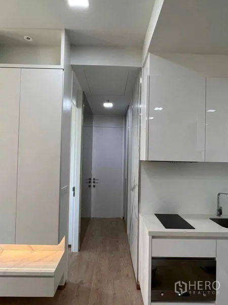 Condominium for rent in Watthana, Bangkok - Hallway from kitchen with glossy cabinetry and wood flooring.