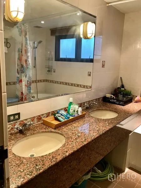 Condominium for rent in Bang Rak, Bangkok - Double-sink vanity with large mirror next to a shower area and window.