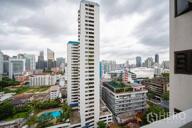 公寓 出售在Watthana, Bangkok - 高楼城市景观，俯瞰素坤逸天际线与下方泳池。