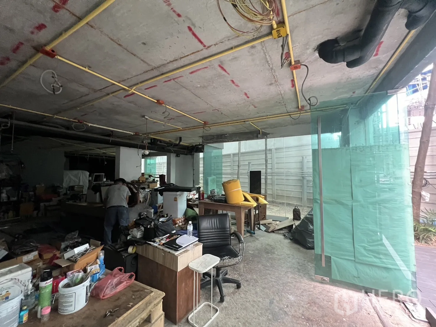 零售空间 出租 - 开间零售内部正在翻新，桌椅与裸露管线，正面为落地玻璃。